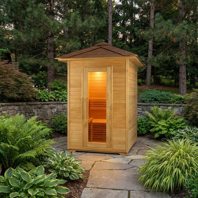 Wooden outdoor sauna surrounded by greenery and a stone pathway.